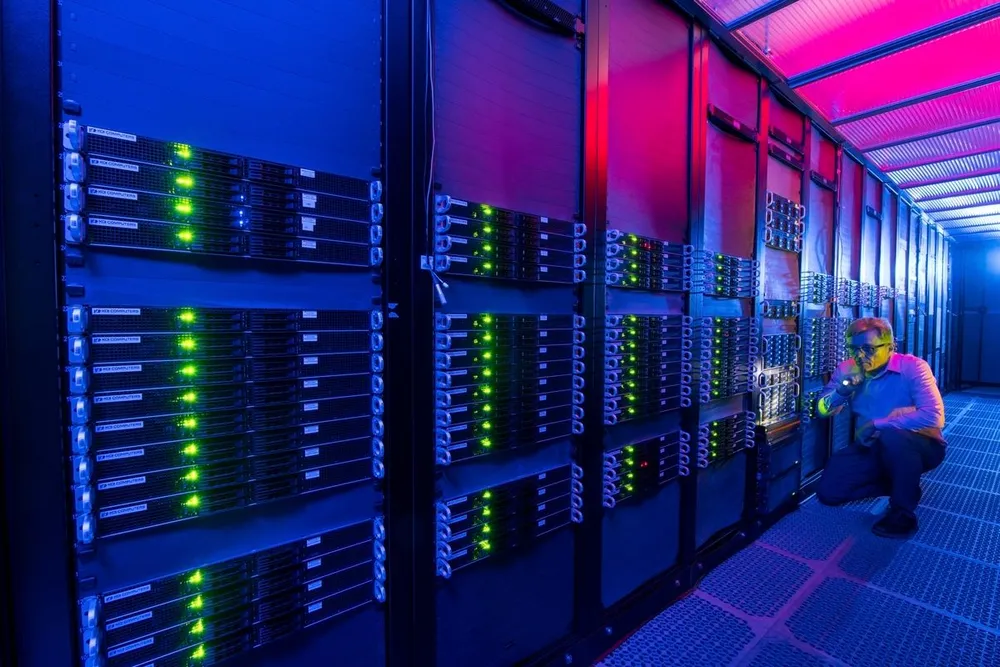 Tier 4-datacenter in België — serverhal met technicus en paarsblauwe randverlichting