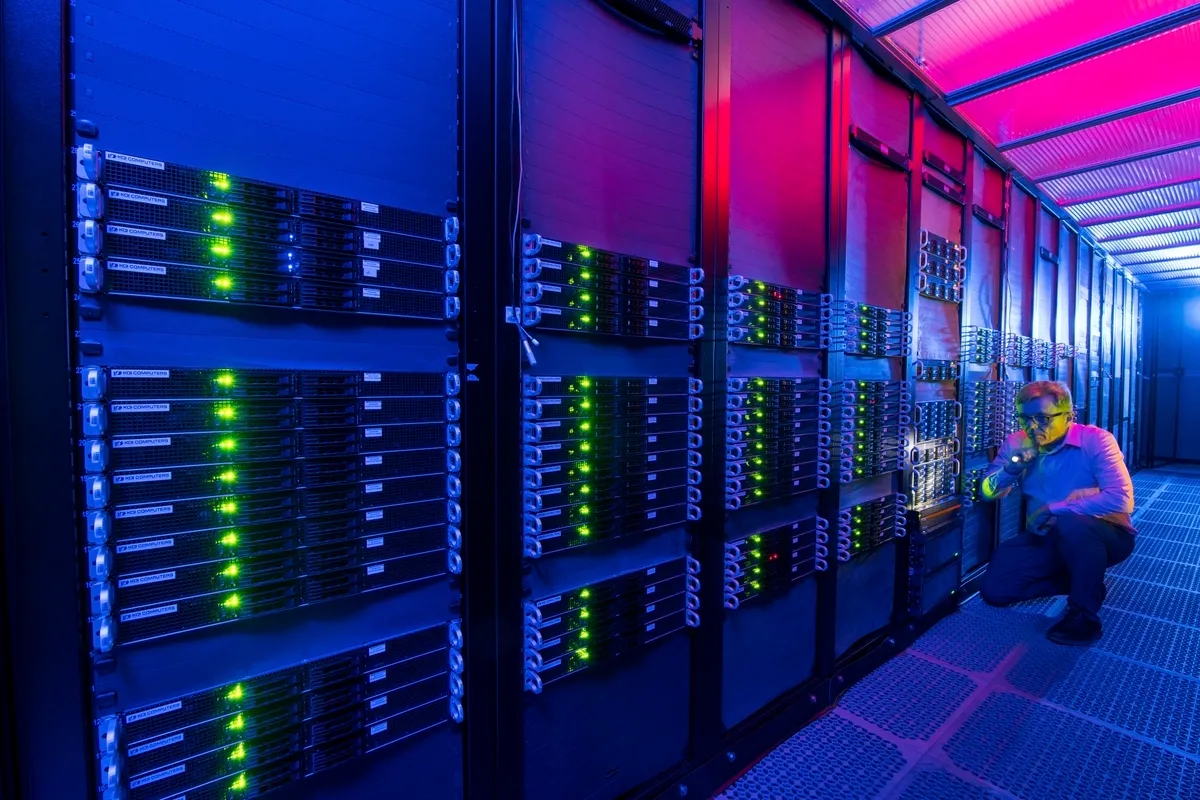 Tier 4-datacenter in België — serverhal met technicus en paarsblauwe randverlichting